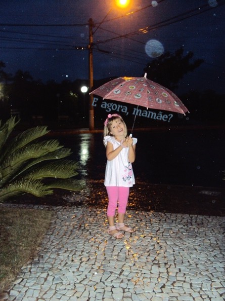 Feliz da vida  porque choveu e ela pôde sair em frente de casa, pra usar o guarda-chuva...